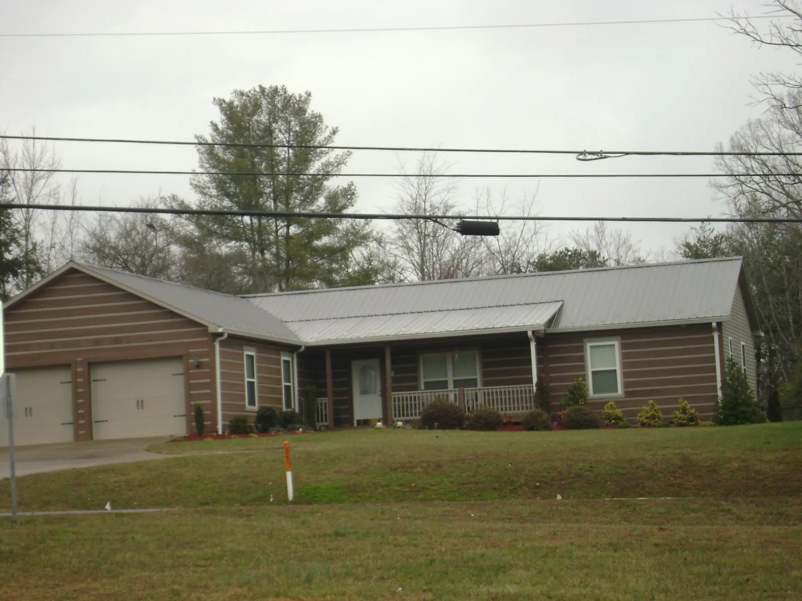 Gray metal roof on a log sided ranch home with a front porch in Jacksonville